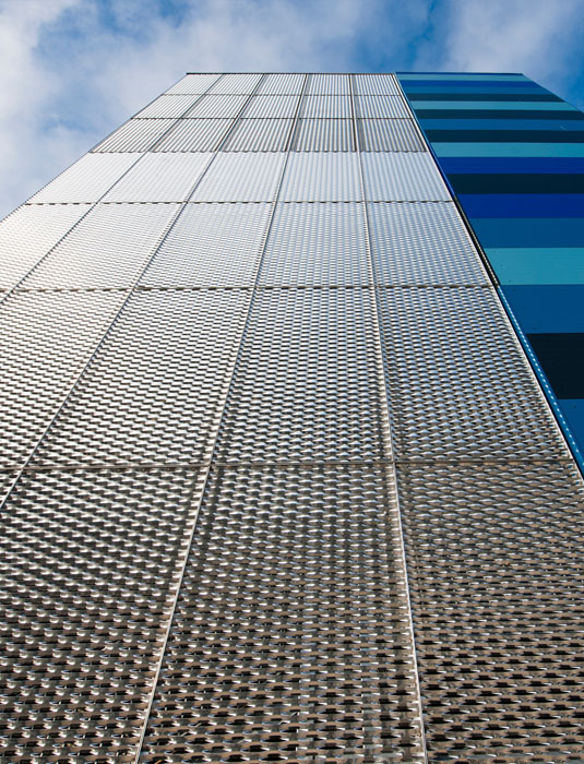 The building facade is designed with white perforated metal sheets.
